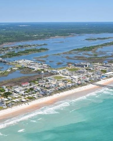 Aerial view of coastal town with beach, turquoise ocean, and inland waterways with green vegetation